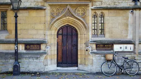 Photo of St Cross College doorway with bicycle and College crest